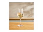 A glass of sparkling white wine on a wooden table with a light background.
