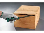 A gloved hand uses a Parkside pry bar to open a wooden crate.