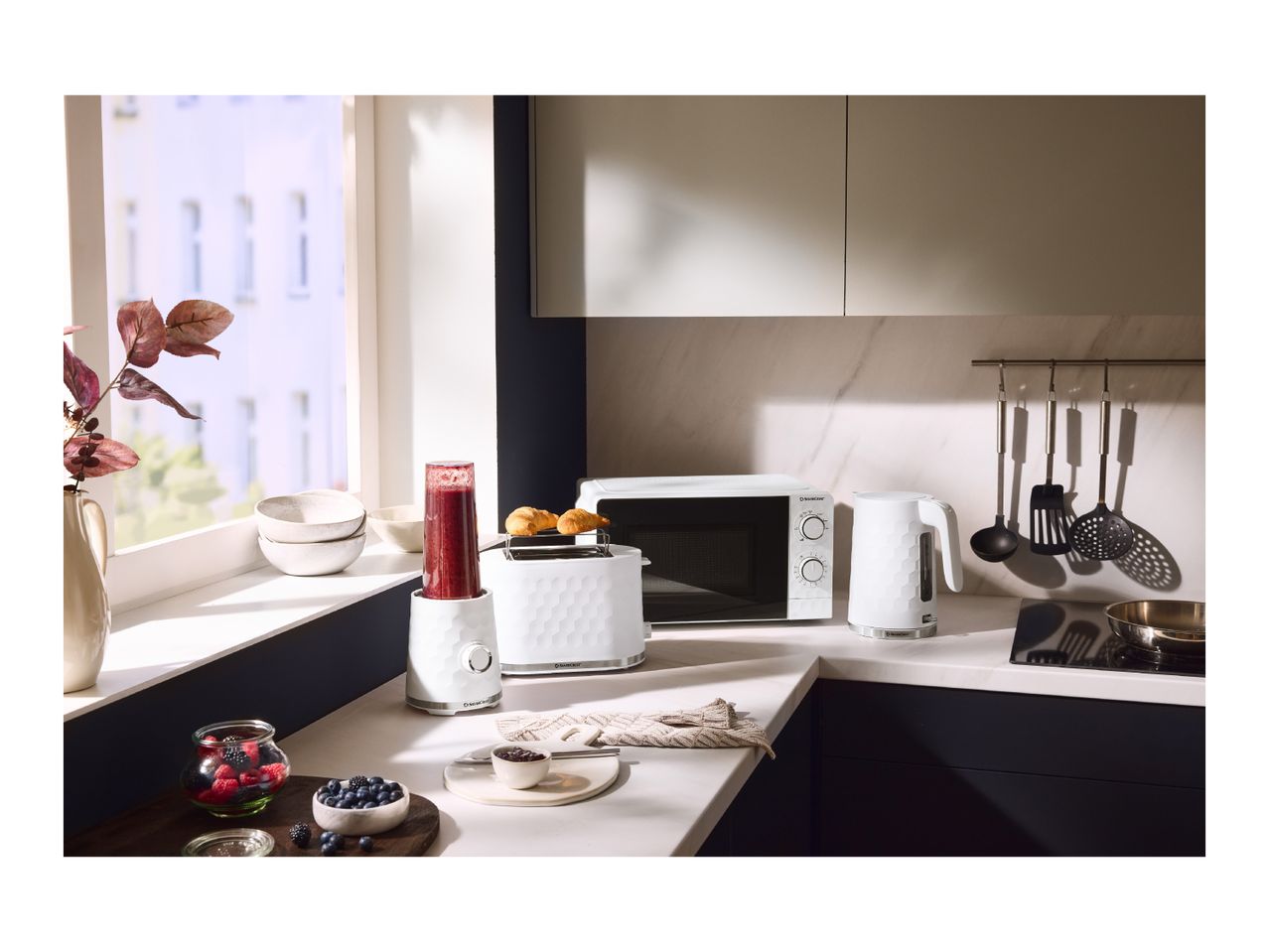 White kitchen appliances including a blender, toaster, microwave, and kettle on a countertop.