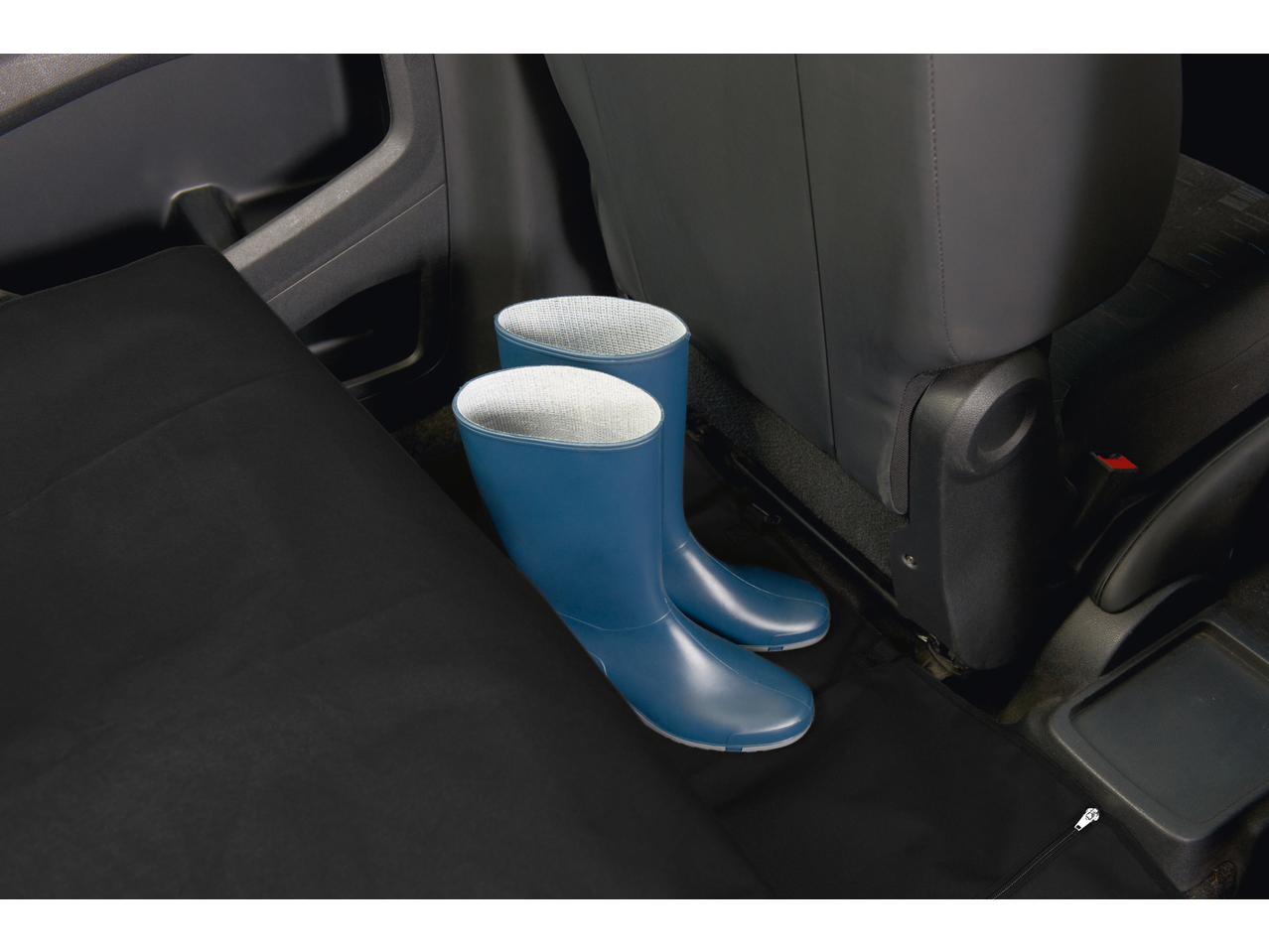 Blue wellington boots on a black car seat protector in the back of a car.