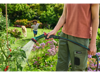 Person watering plants with a Parkside spray gun, with a child and dog in the background.