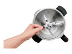 A hand holding the blade of a stainless steel blender from a top-down view.