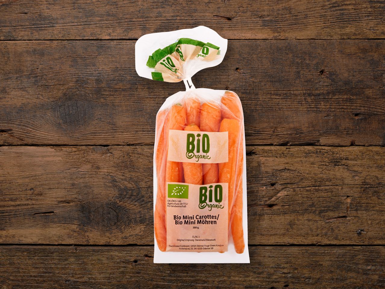 Bio Organic Mini-Karotten in einer Tüte auf Holz.