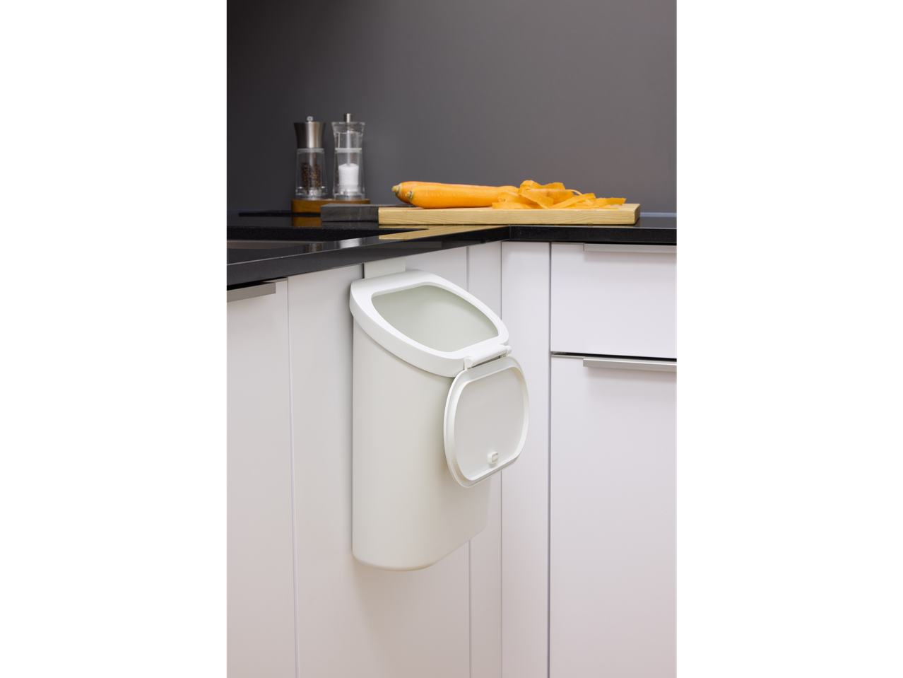 W5 kuhinjski koš za smeti, obešen pod črno delovno ploščo z korenjem.