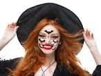 Woman with red hair and witch hat, wearing Halloween face makeup with bats