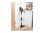 Cordless stick vacuum cleaner mounted on a wall in a modern kitchen setting.
