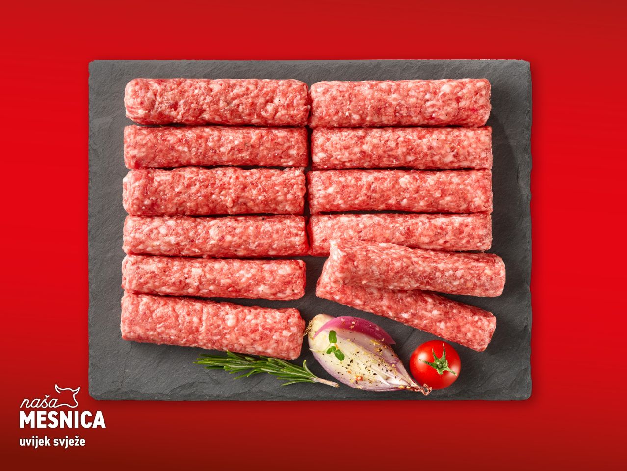 Ćevapi na crnoj ploči s lukom, rajčicom i ružmarinom na crvenoj pozadini.