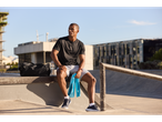 Man resting after workout with bag, towel, and water bottle.