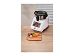 Monsieur Cuisine Smart food processor on a wooden table with vegetables on a cutting board.