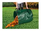 Person emptying a green garden waste bag filled with autumn leaves onto a green lawn.