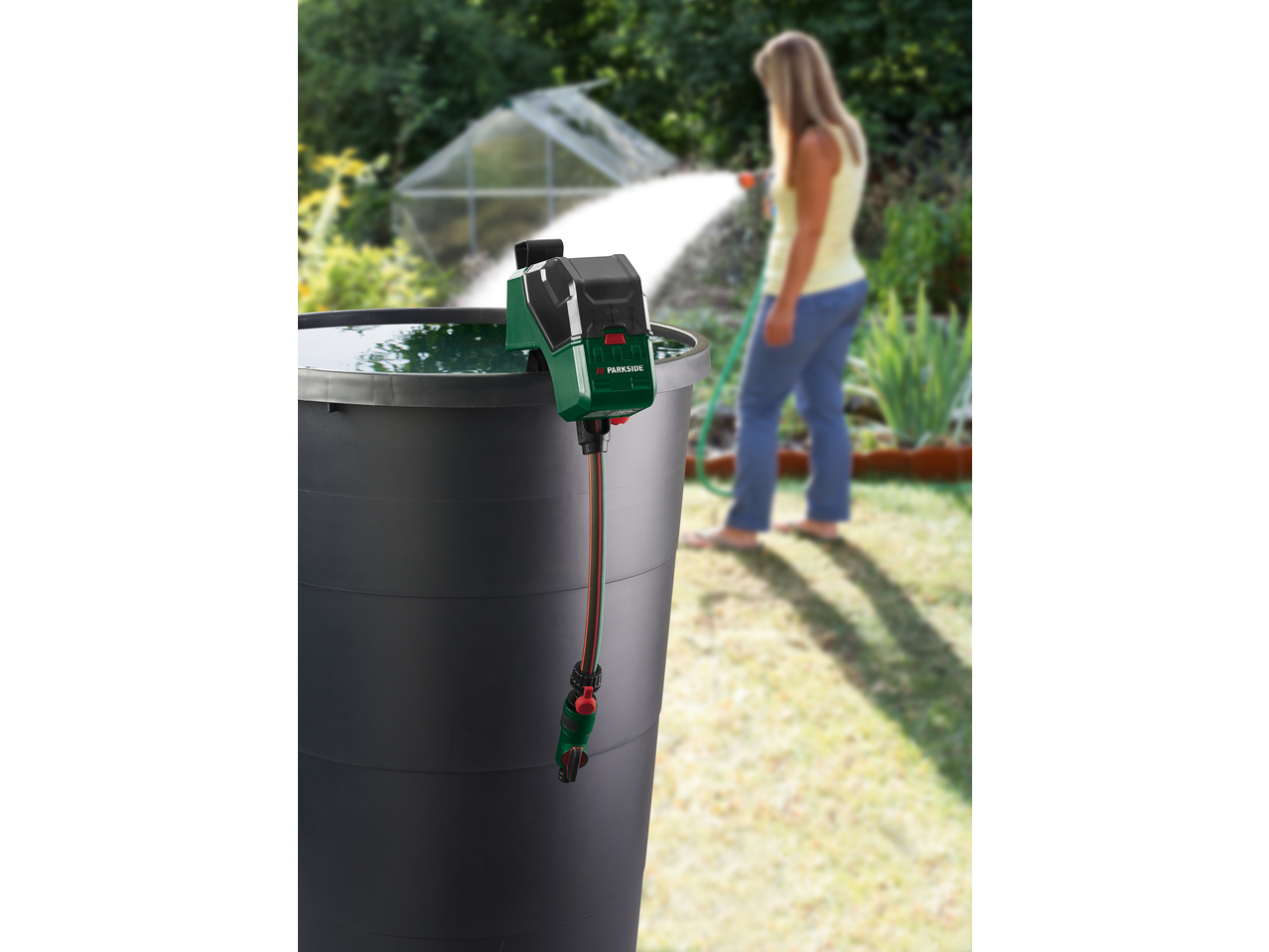 Pompă de apă de ploaie PARKSIDE într-un butoi, udând o grădină.