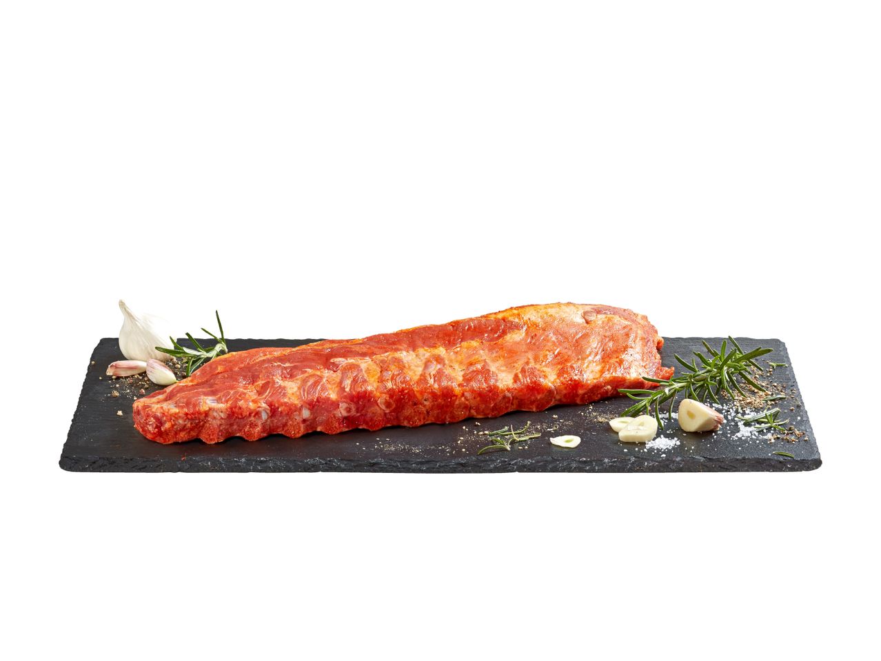 Marinierte Schweinerippchen auf einem schwarzen Schieferstein mit Rosmarin und Knoblauch.
