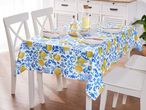 Dining table with a lemon and blue patterned tablecloth, set with plates, glasses, and bottles.