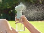 Person using a hand-held misting spray bottle outdoors.