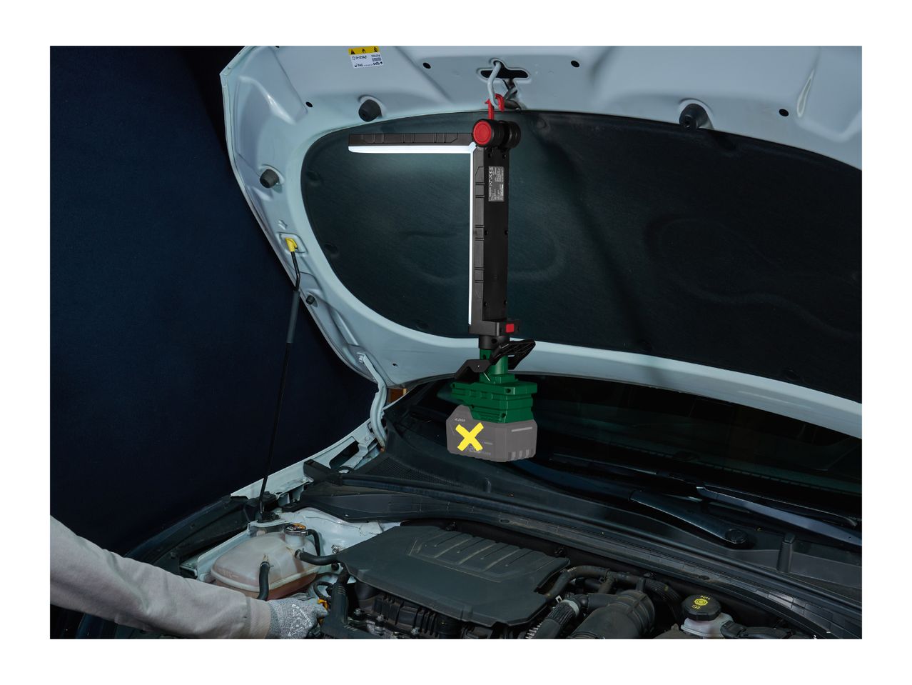 Cordless LED work light hanging from a car hood, illuminating the engine bay