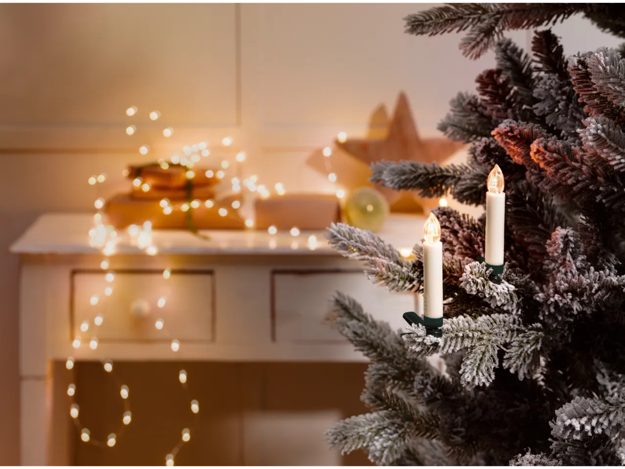 LIVARNO home Wireless LED Christmas Tree Candles on a flocked tree, with blurred gifts and lights in the background.