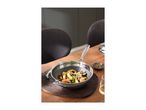 Stainless steel wok with stir-fry, spatula, and spices on a wooden table.