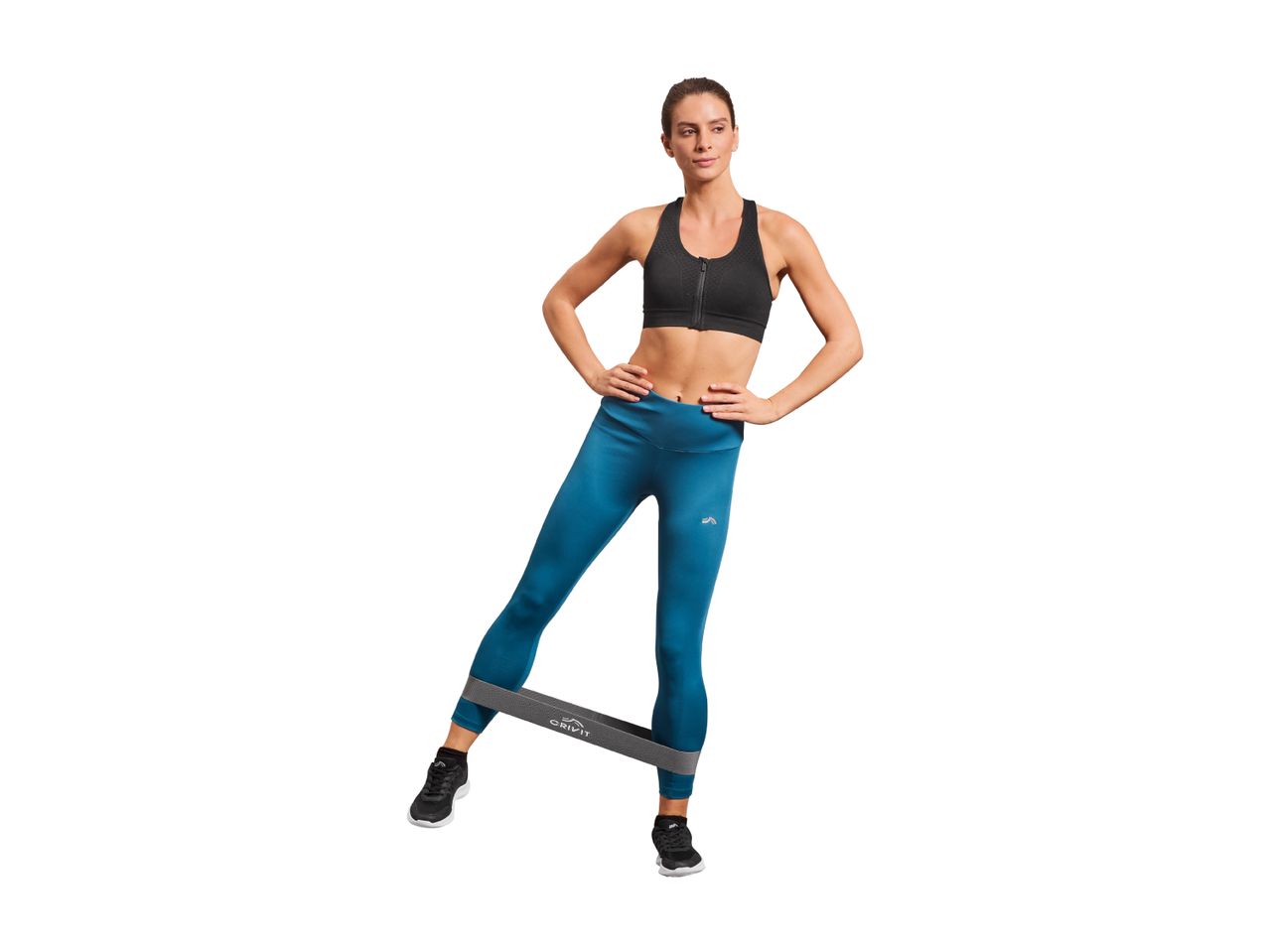 Woman in a black sports bra and blue leggings exercising with a resistance band.