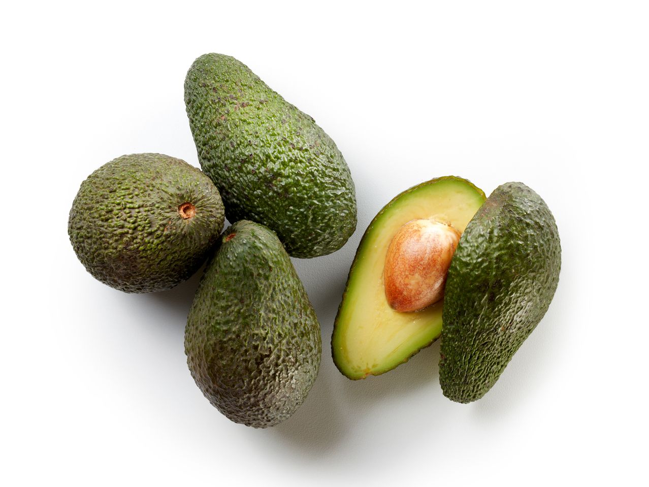 Tre avocado interi e uno tagliato a metà su sfondo bianco.