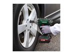 Cordless impact wrench being used to loosen a car wheel nut.