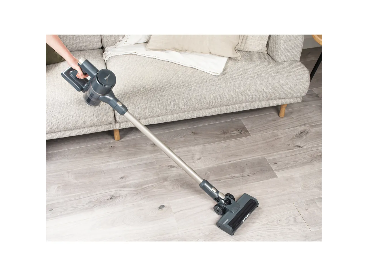 Beldray Cordless Vacuum Cleaner cleaning a light wood floor next to a grey sofa.