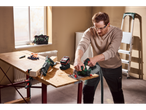 Man cutting wood with a cordless circular saw, with a reciprocating saw nearby.