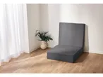 Sedia pieghevole grigia in una stanza con pavimento in legno e tenda bianca.