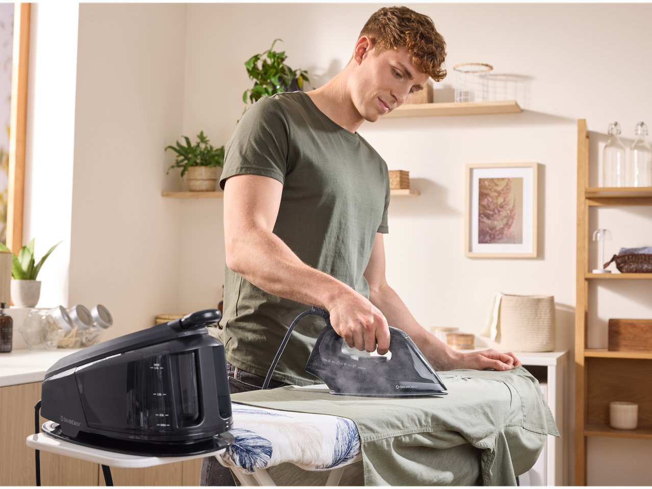 Homem passando uma camisa com um ferro a vapor SilverCrest numa tábua de passar.