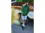 Un bărbat cu un hanorac verde Parkside și adidași verzi stă lângă o camionetă.