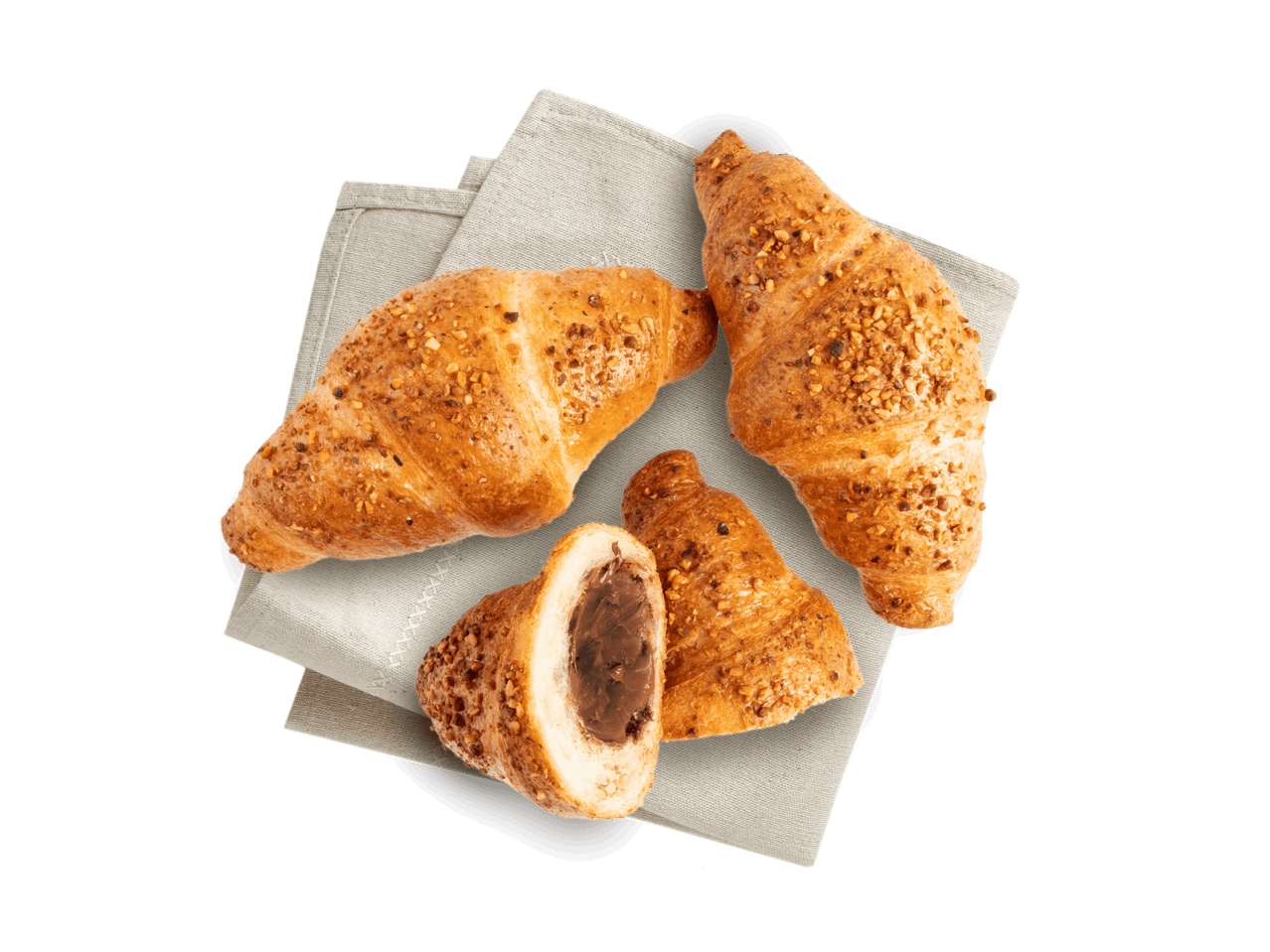 Drei Haselnuss-Croissants, eines davon halbiert mit Schokoladenfüllung, auf einem Tuch.