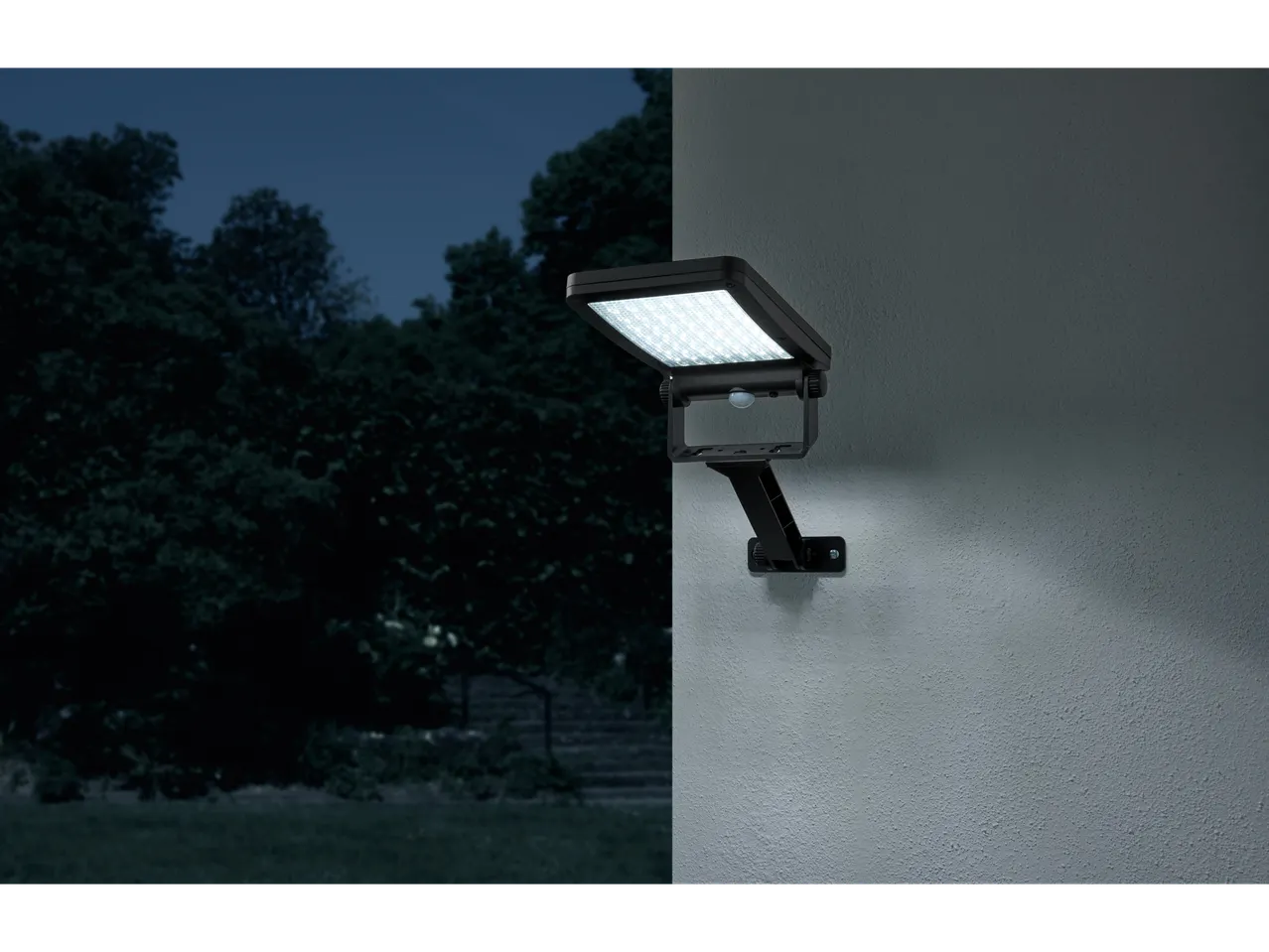 Lampă LED neagră de exterior cu senzor de mișcare montată pe un perete noaptea.