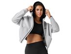 Woman in a light gray zip-up hoodie and black sports bra with black leggings.