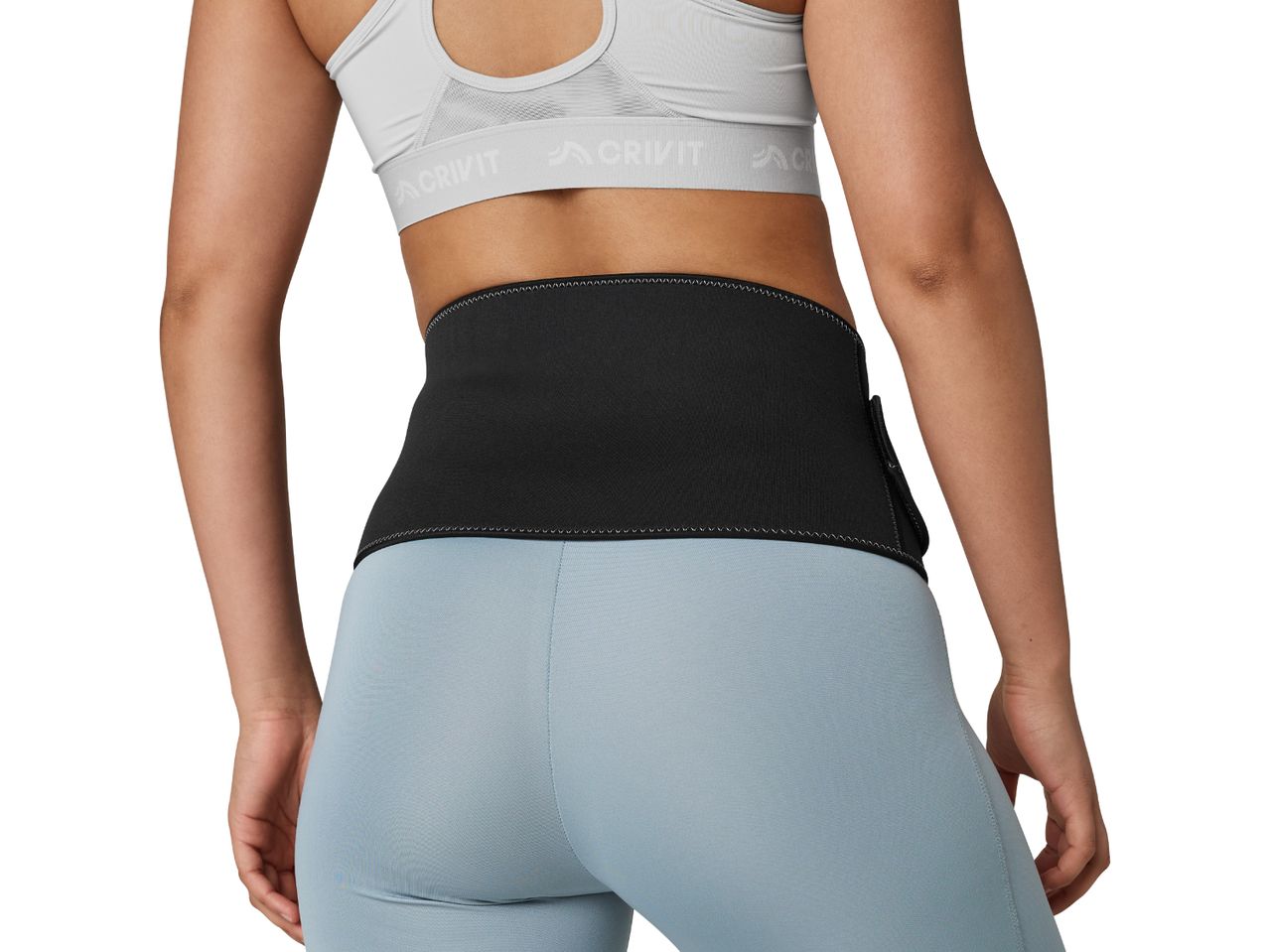 A woman from behind wearing a black waist trimmer, light blue leggings, and a grey sports bra.