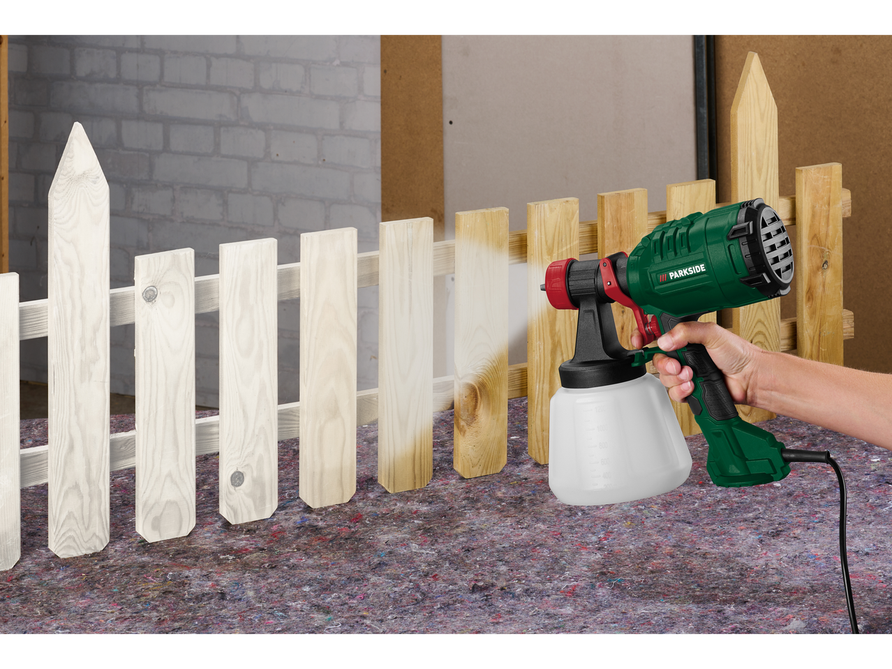 Parkside HVLP pištola za barvanje, ki barva leseno ograjo v belo