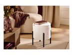 White bouclé ottoman with black legs, a red book on top, in a cozy living room.