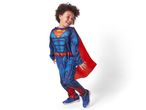 A young boy in a blue and red Superman costume with a red cape, smiling.
