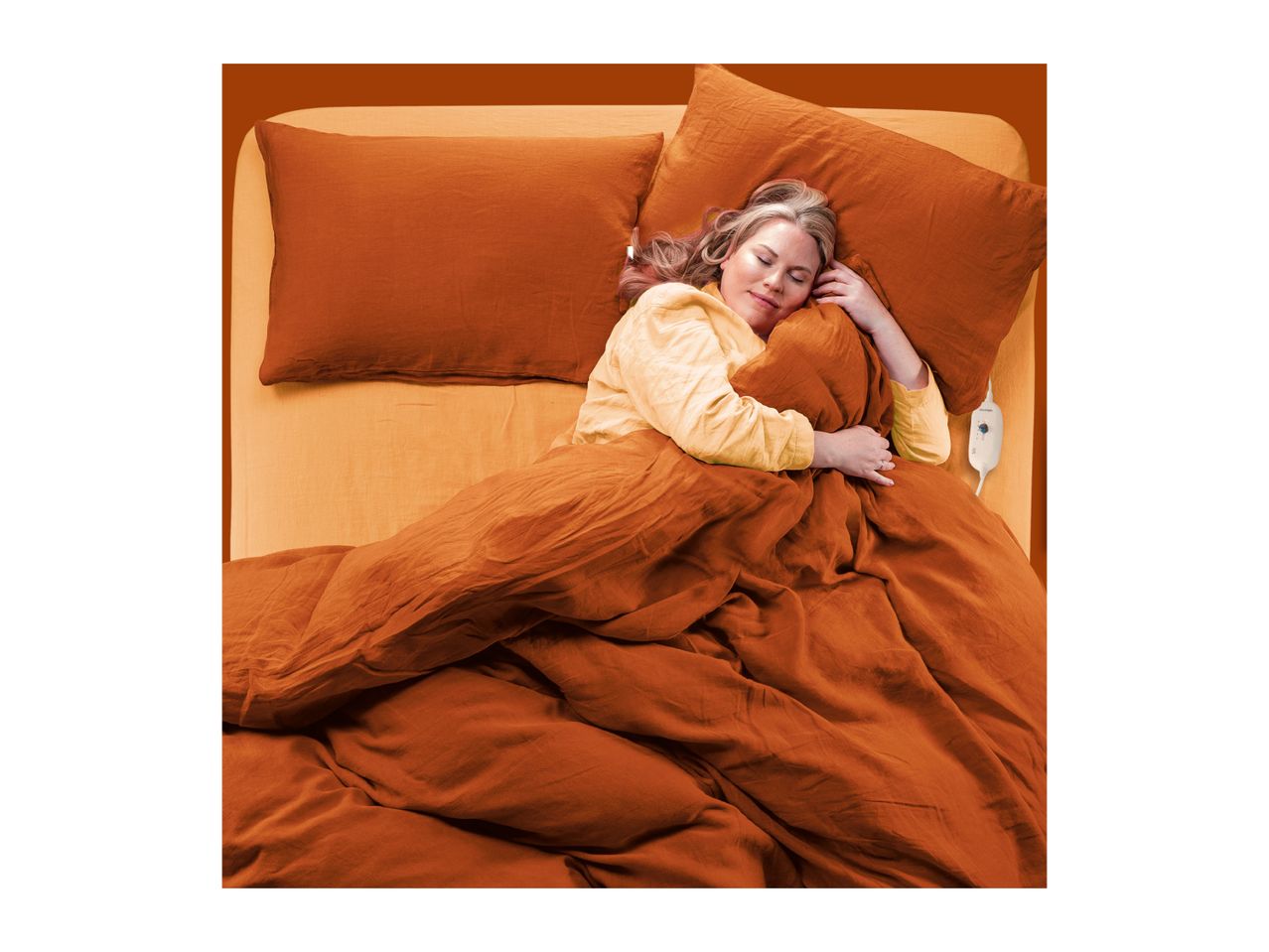 A woman sleeping comfortably in a bed with orange linen sheets and pillows.