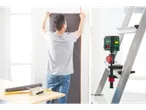 Un bărbat montează tapet, în timp ce un nivel laser este fixat pe o scară.