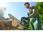 Man in safety gear cutting wood with a Parkside chainsaw outdoors.