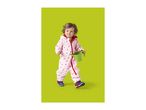 Toddler in a pink heart-patterned waterproof suit holding a green watering can.