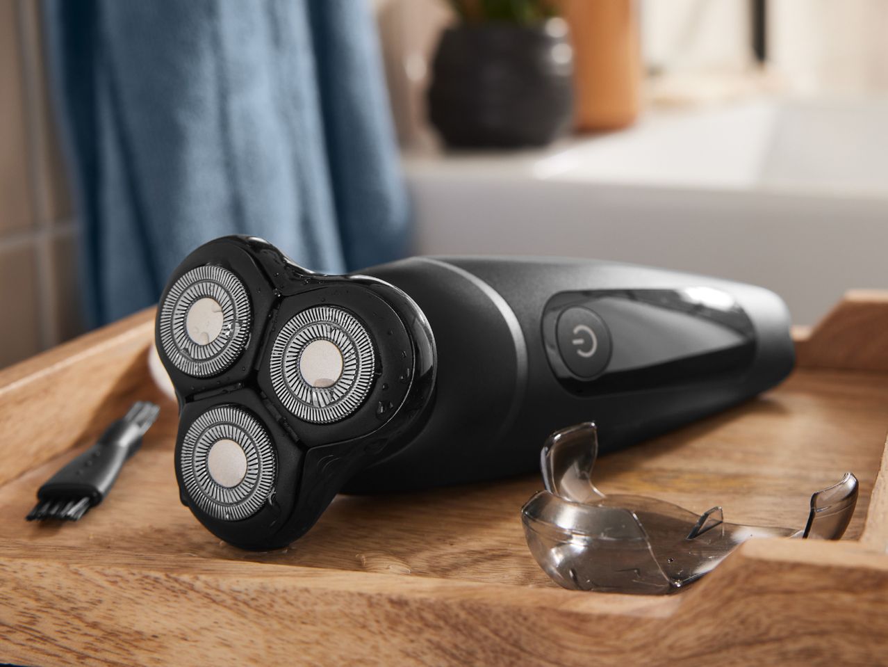 A Braun three-head electric razor rests on a wooden surface.