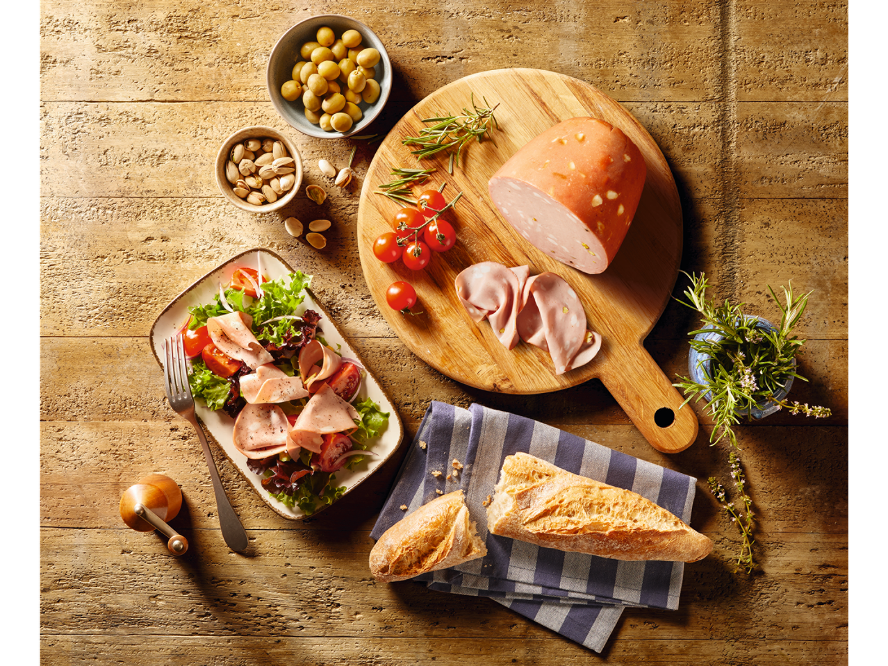 Mortadella, salade en brood op een rustieke houten tafel.