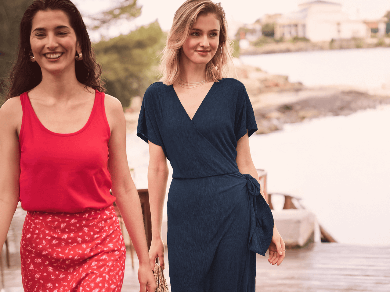Zwei Frauen tragen sommerliche Kleidung: ein rotes Top und einen Wickelrock, ein dunkelblaues Wickelkleid.