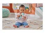 Baby playing with a fox rattle on a patterned rug.