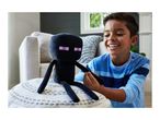 A boy playing with a black plush toy with pink eyes, sitting on a white knitted pouf.