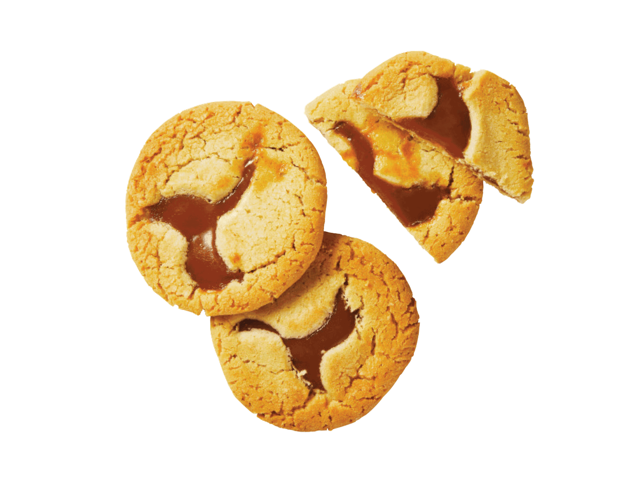 Trīs karameļu pildījuma cepumi, viens no tiem salauzts, uz melna fona.