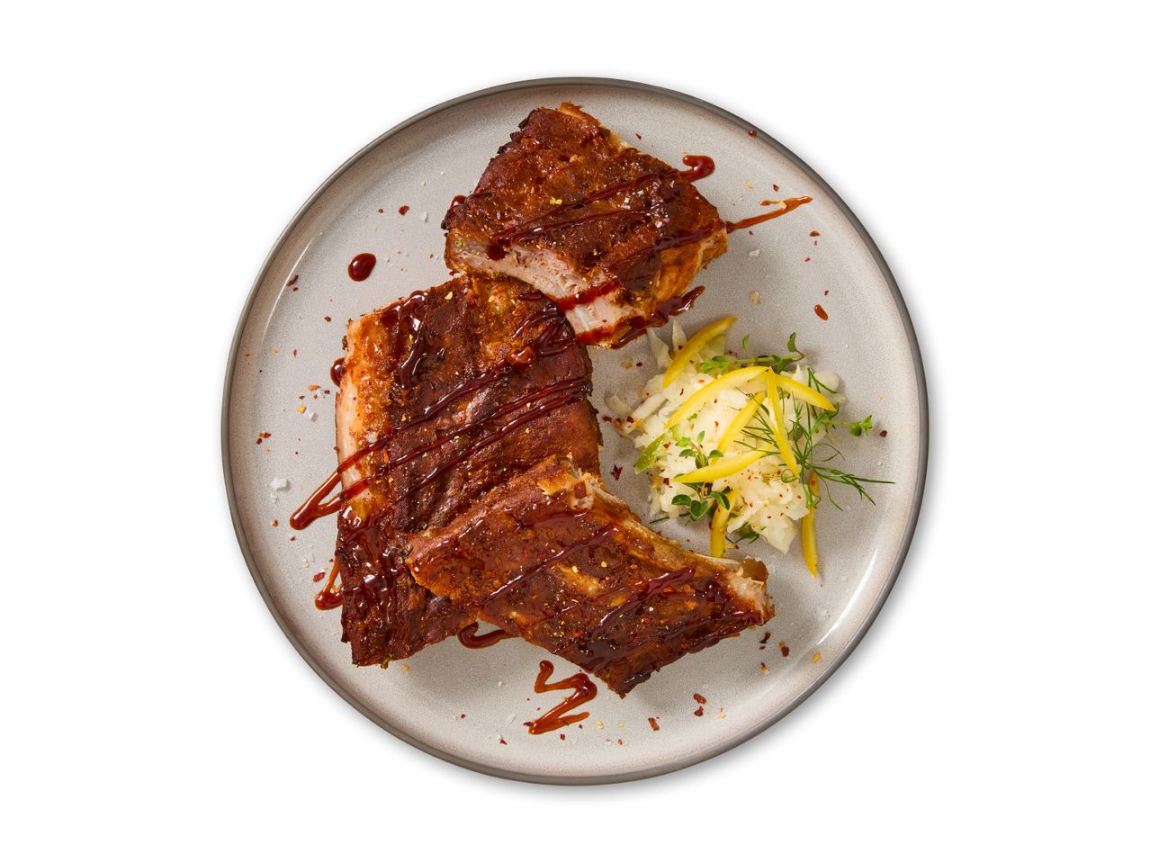 Grillribben med barbecuesauce og kålsalat på en grå tallerken.