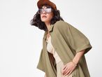 Жена, облечена в риза цвят каки и кафява шапка.