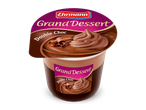 Een chocoladedessert in een beker met chocoladekrullen en een toef chocolademousse, met de tekst 'Grand Dessert Double Choc'.