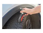 A person using a digital tire tread depth gauge on a car tire.